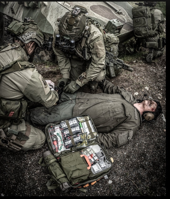 Combat medics treating casualty near armored vehicle